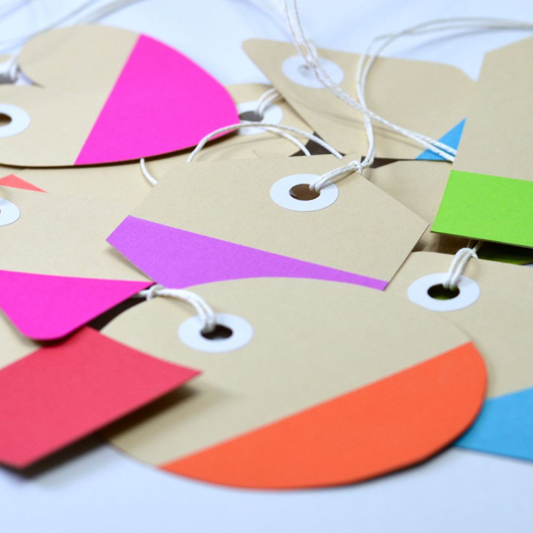 A collection of colorful tags in various shapes, tied with strings.