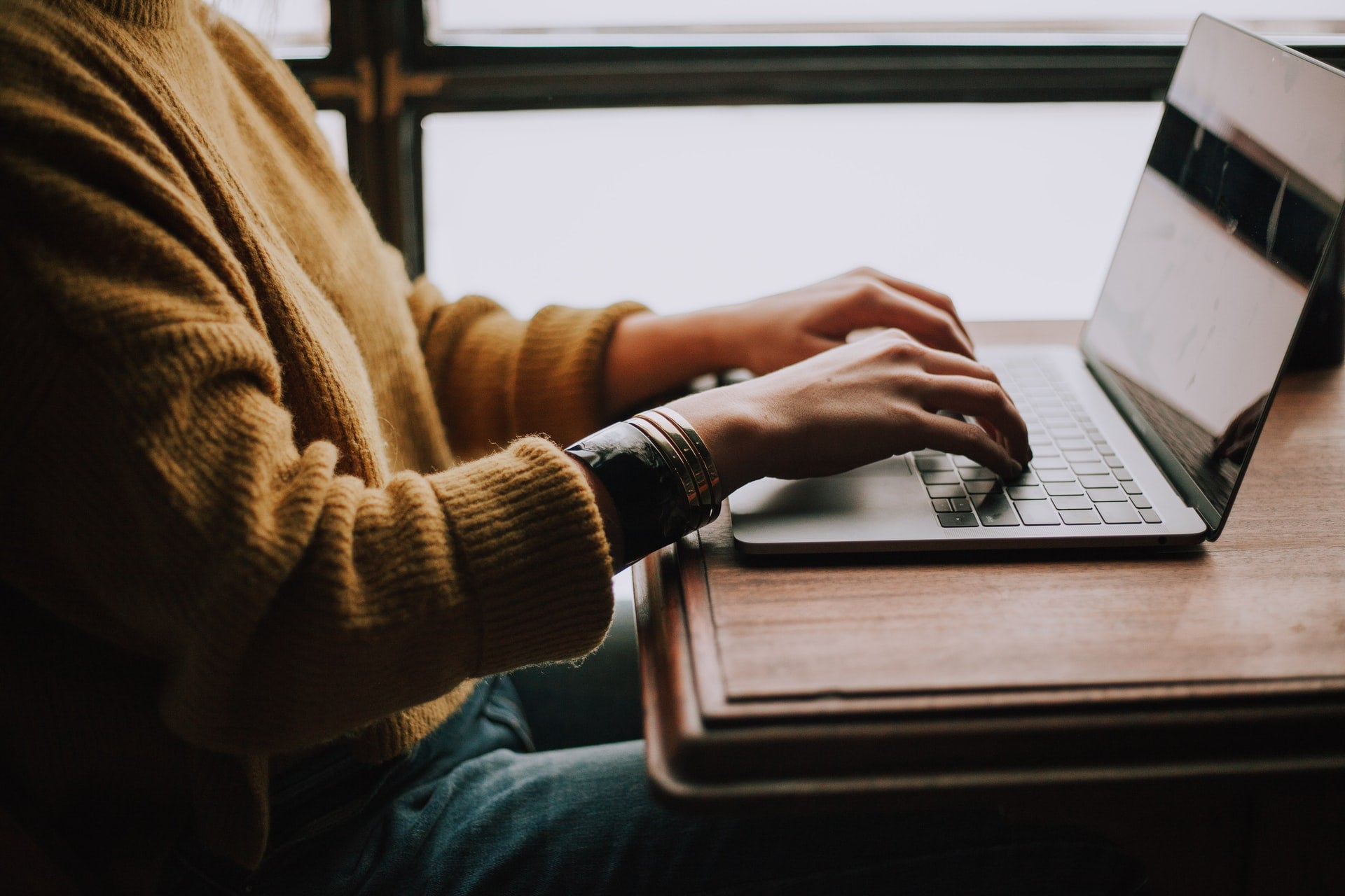 a person typing at a computer at a wooden desk