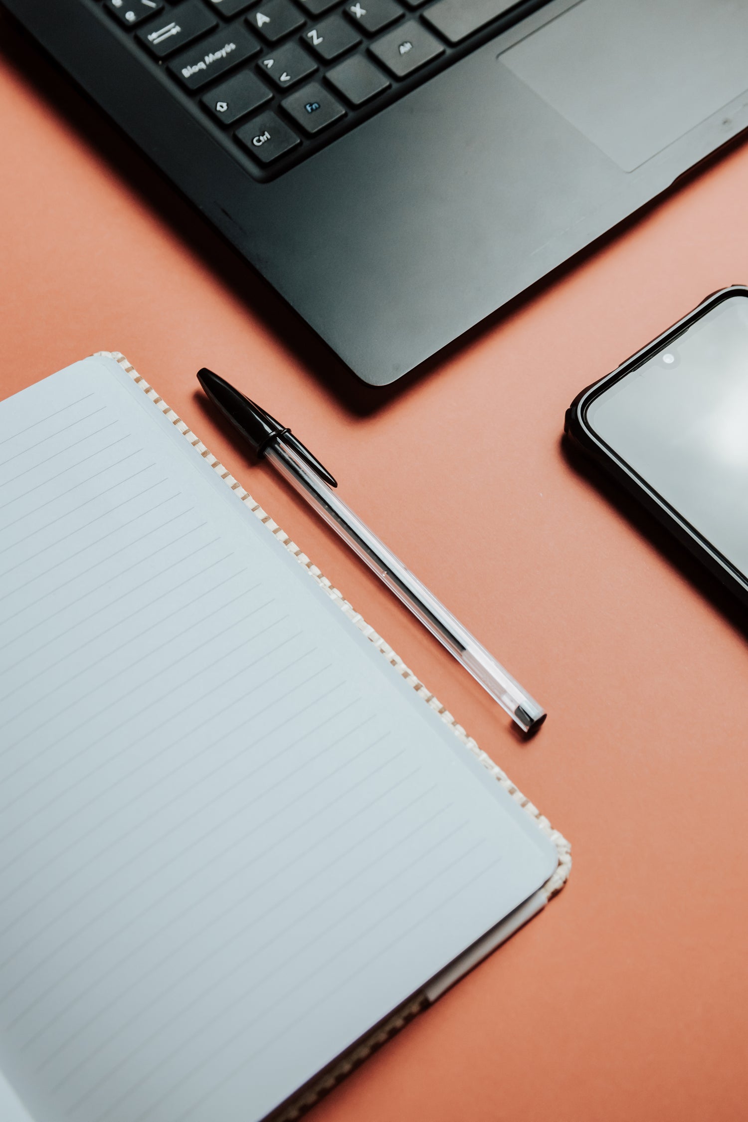overhead view of a notebook lying flat and a pen beside it.