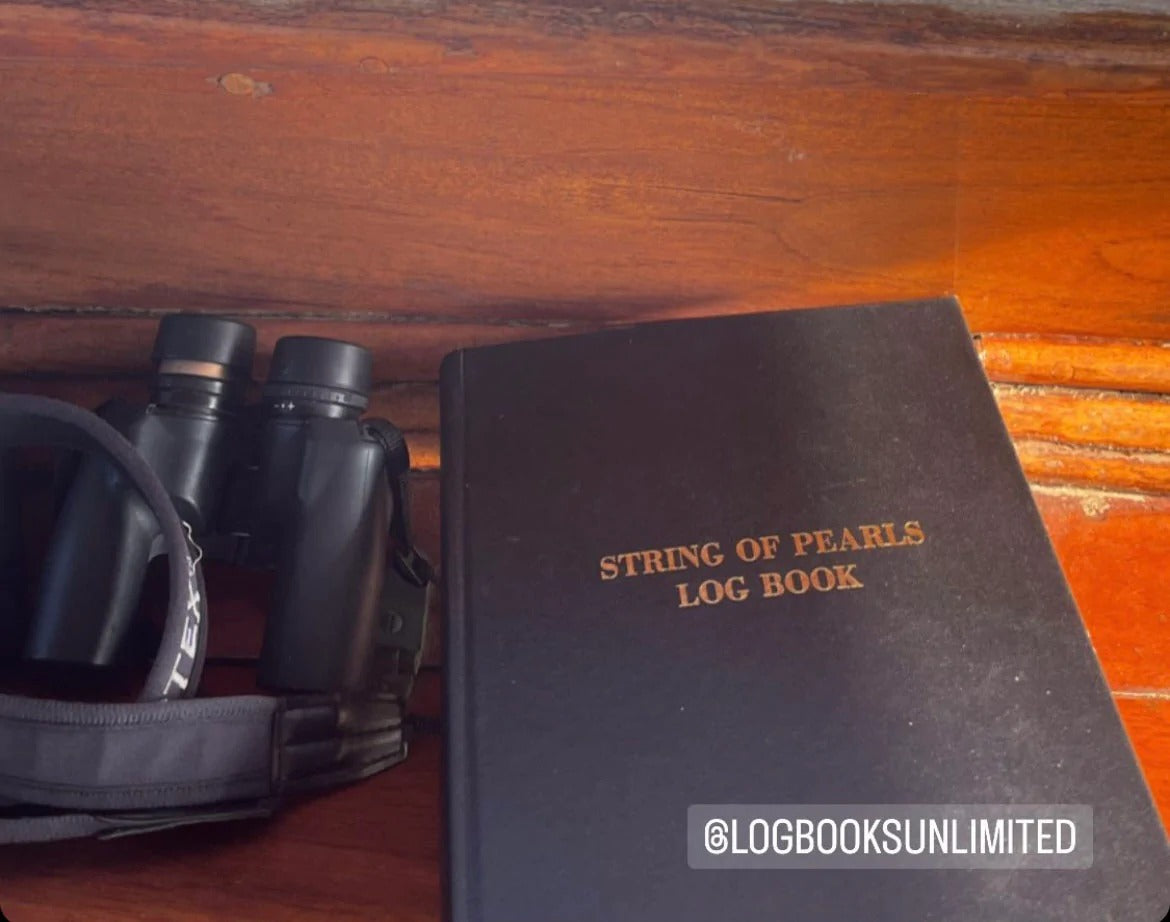 a black log book beside a pair of binoculars