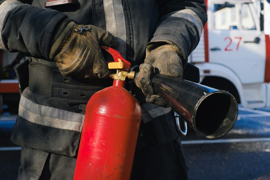 A firefighter holding a red fire extingusher