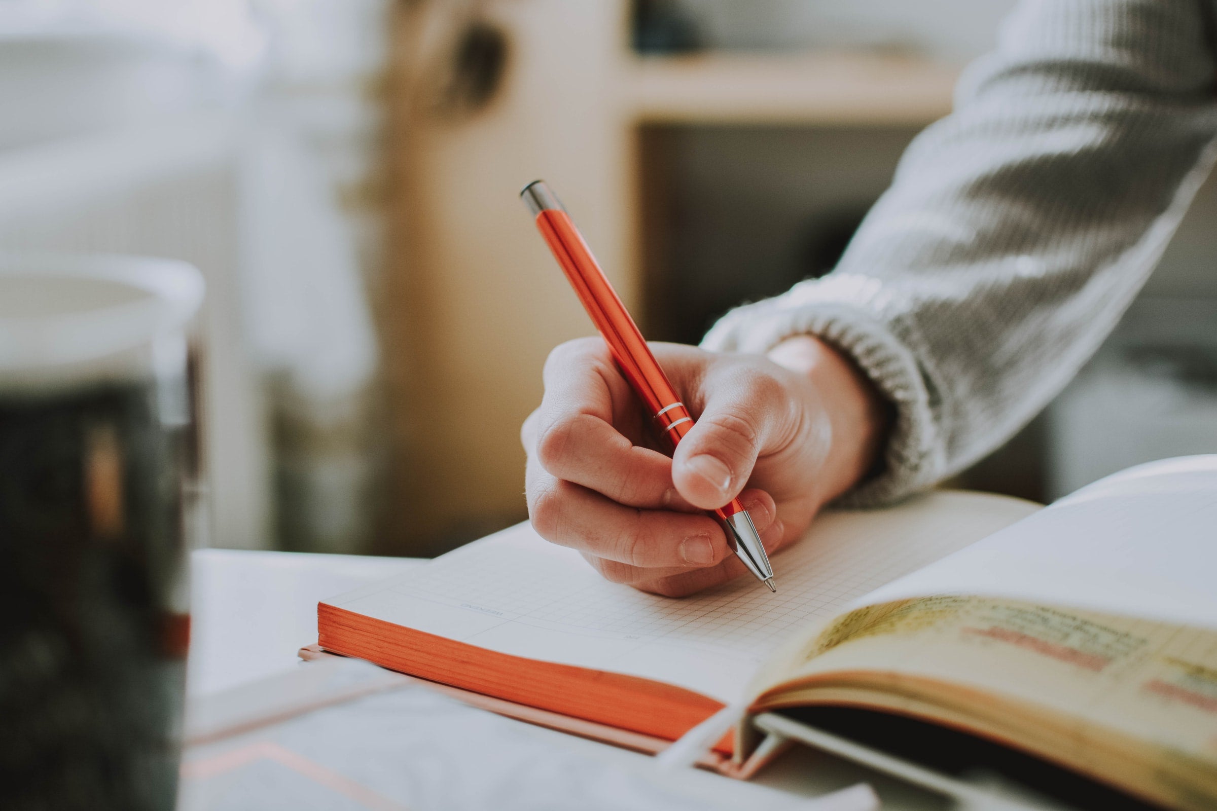 a person writing in a log book with a red pen