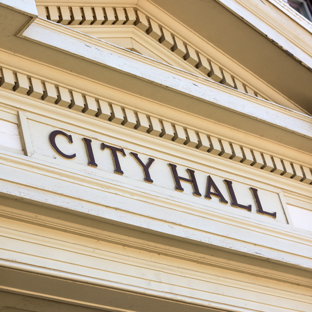 A close-up of a decorative sign reading "CITY HALL" on a building facade.