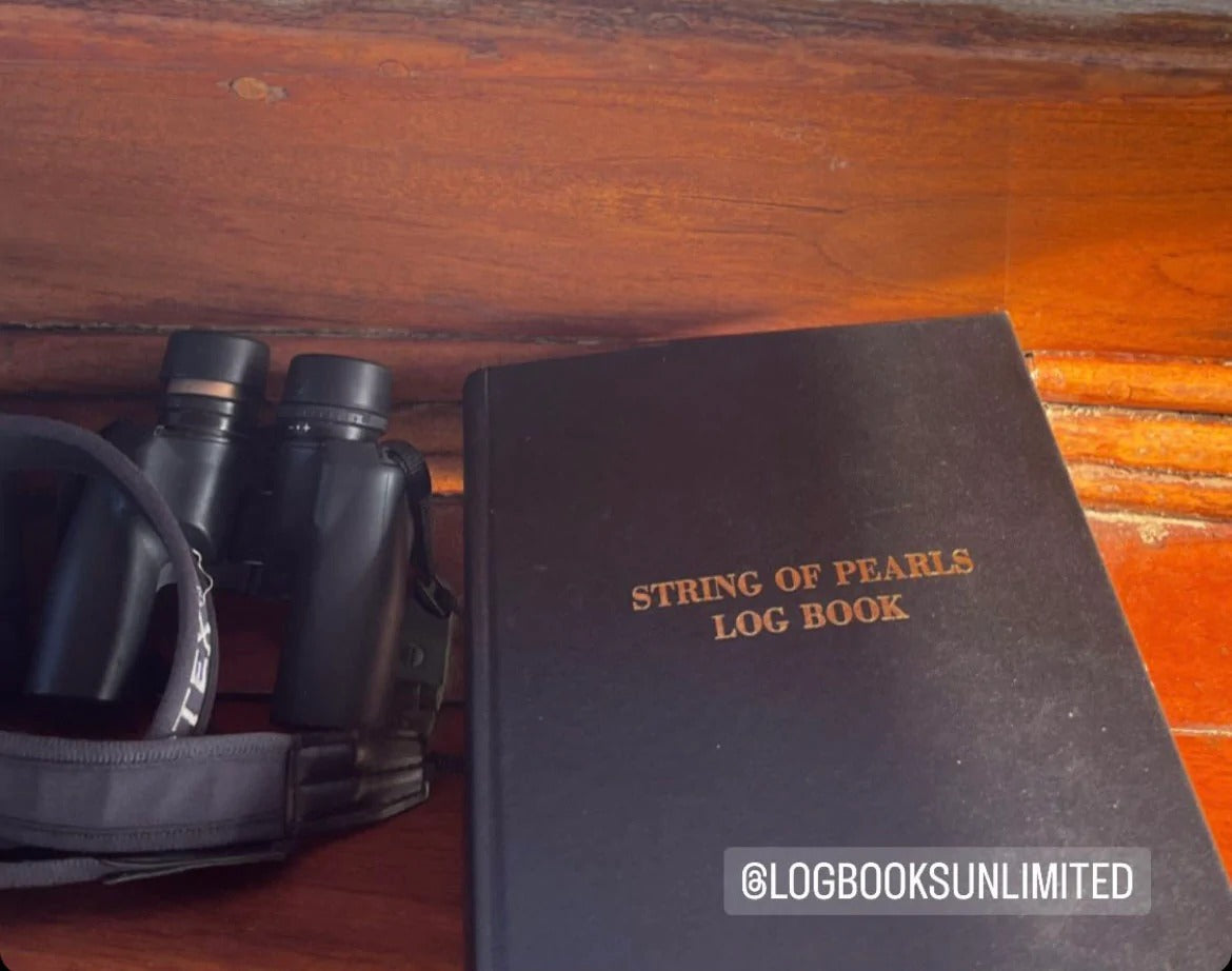 a black log book beside a pair of binoculars 