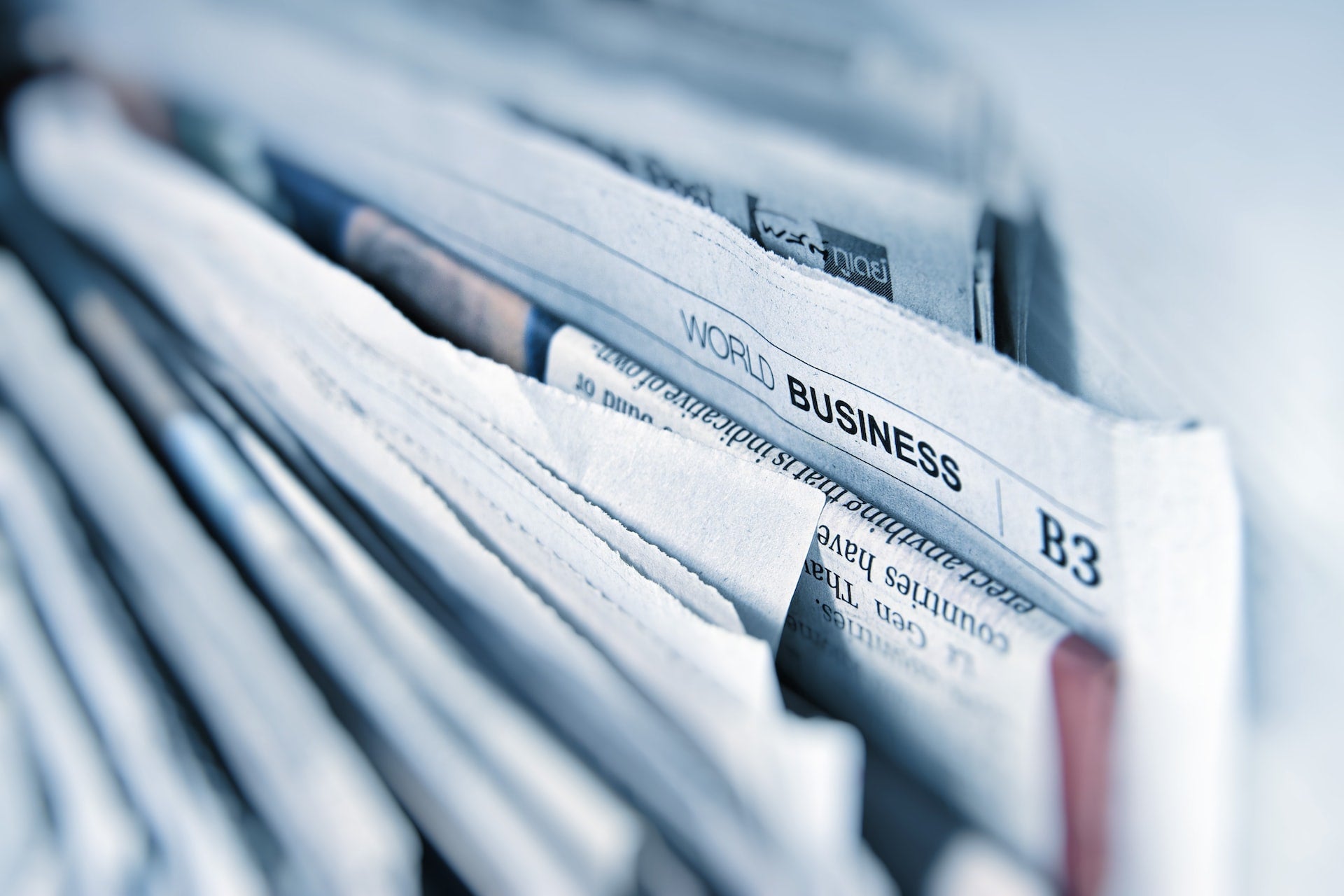 a stack of newspapers together with one saying business at the top