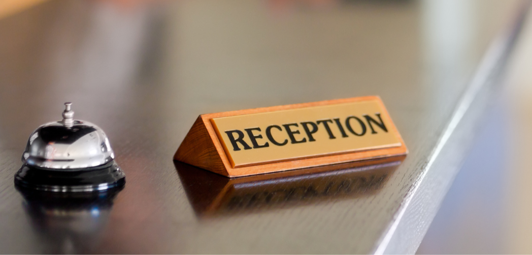 A close-up picture of a reception sign and a bell.