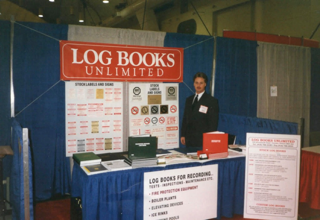 Jim Barratt at a convention with a blue Log Books Unlimited booth